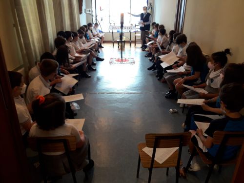 Grupo de alumnos sentados en el oratorio con su libro de oraciones de la mano